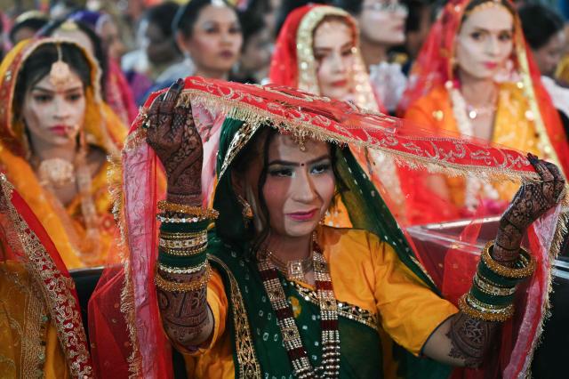 A Pakistani Hindu bride raises her veil during a mass marriage ceremony organised by the  Cutchi Maheshwari Welfare Association in Karachi on May 8, 2026. (Photo by Rizwan TABASSUM / AFP)