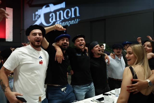 People sing during a big banquet organised by the 'Canon francais' in Montelimar, south-eastern France, on May 8, 2026. The banquets of the 'Canon francais', which draw thousands of guests around roast pork and red wine to "promote local traditions and heritage," are accused by their critics of spreading racist ideas behind their patriotic, typically French image. (Photo by Alex MARTIN / AFP)
