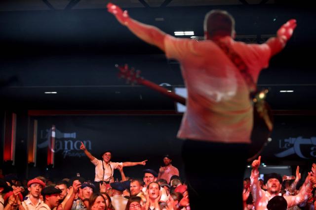 People enjoy a concert during a big banquet organised by the 'Canon francais' in Montelimar, south-eastern France, on May 8, 2026. The banquets of the 'Canon francais', which draw thousands of guests around roast pork and red wine to "promote local traditions and heritage," are accused by their critics of spreading racist ideas behind their patriotic, typically French image. (Photo by Alex MARTIN / AFP)