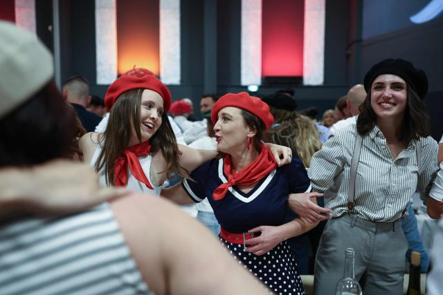 People dance during a big banquet organised by the 'Canon francais' in Montelimar, south-eastern France, on May 8, 2026. The banquets of the 'Canon francais', which draw thousands of guests around roast pork and red wine to "promote local traditions and heritage," are accused by their critics of spreading racist ideas behind their patriotic, typically French image. (Photo by Alex MARTIN / AFP)