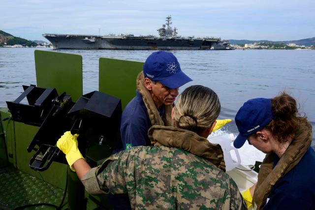 Members of Brazil's Naval Secretariat for Nuclear Safety and Quality collect water samples near the USS Nimitz (CVN-68) aircraft carrier as part of a safety protocol carried out whenever nuclear-powered naval vessels operate or visit the Brazilian coast, in Guanabara Bay in Rio de Janeiro, Brazil, on May 8, 2026. (Photo by Pablo PORCIUNCULA / AFP)