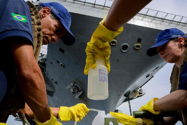 Members of Brazil's Naval Secretariat for Nuclear Safety and Quality collect water samples near the USS Nimitz (CVN-68) aircraft carrier as part of a safety protocol carried out whenever nuclear-powered naval vessels operate or visit the Brazilian coast, in Guanabara Bay in Rio de Janeiro, Brazil, on May 8, 2026. (Photo by Pablo PORCIUNCULA / AFP)