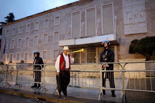 A protester wearing traditional Albanian clothes plays vuvuzela in front of Albanian riot police officers during an anti-government protest in Tirana on May 8, 2026. (Photo by Adnan Beci / AFP)