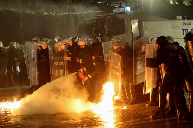 Albanian riot police officers use a fire extinguisher to put out a fire after being targeted with Molotov cocktails during an anti-government protest in Tirana on May 8, 2026. (Photo by Adnan Beci / AFP)