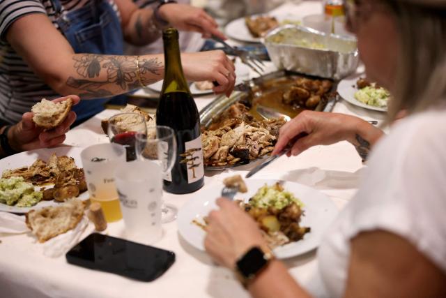 Attendees eat during a big banquet organised by the 'Canon francais' in Montelimar, south-eastern France, on May 8, 2026. The banquets of the 'Canon francais', which draw thousands of guests around roast pork and red wine to "promote local traditions and heritage," are accused by their critics of spreading racist ideas behind their patriotic, typically French image. (Photo by Alex MARTIN / AFP)