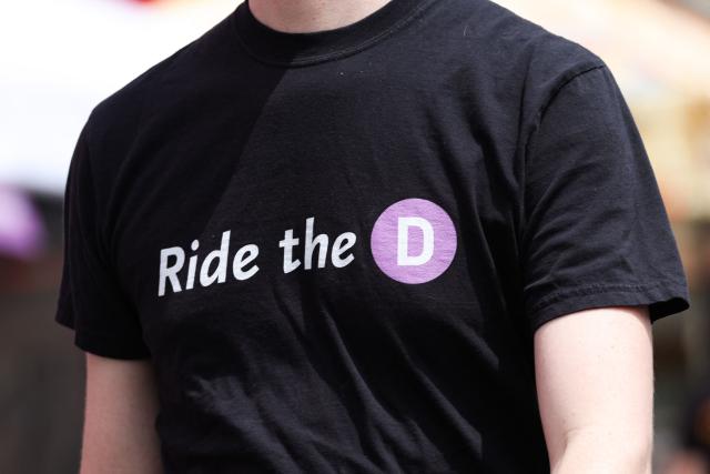 A person wears a "Ride the D" t-shirt during the opening of the Metro D Line subway extension in Los Angeles on May 8, 2026. The transit extension adds three new stations along Wilshire Boulevard to Beverly Hills ahead of the 2026 FIFA World Cup with two more extensions of the rail line planned to be completed before the 2028 Summer Olympics. (Photo by Patrick T. Fallon / AFP)