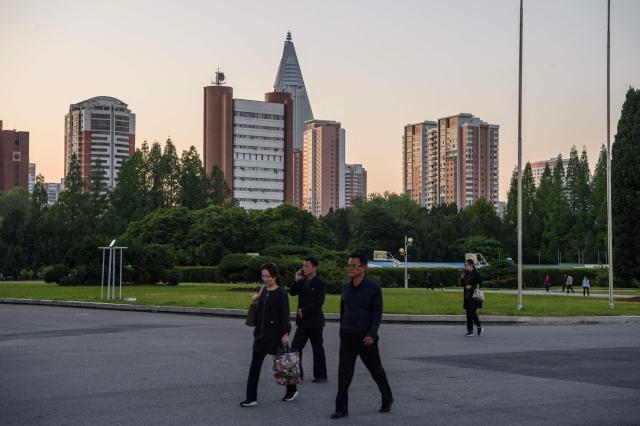 People walk along a street with the landmark Ryugyong Hotel building (back top C) in view in Pyongyang on May 8, 2026. (Photo by KIM Won Jin / AFP)