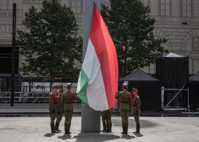 Honour guards raise a flag of Hungary ahead of the arrivals of politicians at Kossuth Square for the inaugural session of the new Parliament and the ceremonial swearing in of representatives in Budapest on May 9, 2026. Hungarian parliament's inaugural session on May 9, 2026, will see a record number of women, accounting for more than a quarter of lawmakers, and more than a hundred deputies new to politics. (Photo by Ferenc ISZA / AFP)