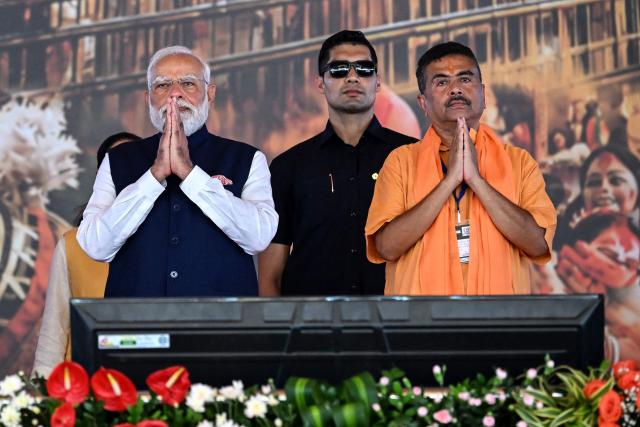 Newly elected Chief Minister of West Bengal state, Suvendu Adhikari (R), along with India's Prime Minister Narendra Modi (L), greets supporters during his swearing-in ceremony in Kolkata on May 9, 2026. (Photo by Dibyangshu SARKAR / AFP)