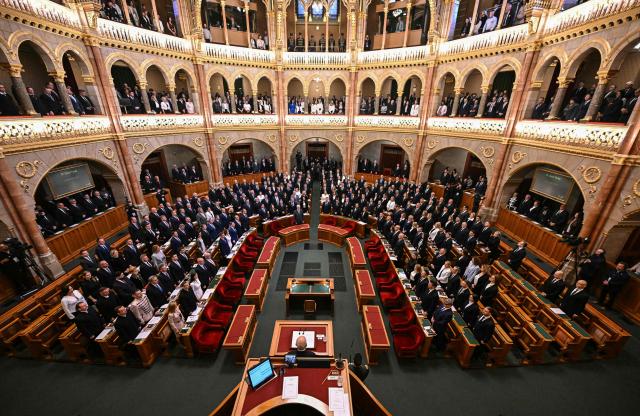 Hungarian politicians stand for the national anthem at the start of the inaugural session of the new Parliament and the ceremonial swearing in of representatives in Budapest on May 9, 2026. Hungarian parliament's inaugural session on May 9, 2026, will see a record number of women, accounting for more than a quarter of lawmakers, and more than a hundred deputies new to politics. (Photo by Attila KISBENEDEK / AFP)