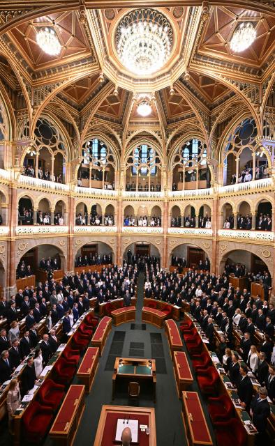 Hungarian politicians stand for the national anthem at the start of the inaugural session of the new Parliament and the ceremonial swearing in of representatives in Budapest on May 9, 2026. Hungarian parliament's inaugural session on May 9, 2026, will see a record number of women, accounting for more than a quarter of lawmakers, and more than a hundred deputies new to politics. (Photo by Attila KISBENEDEK / AFP)