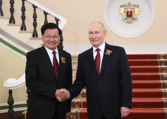 In this pool photograph distributed by the Russian state agency Sputnik, Russia's President Vladimir Putin welcomes Laotian President Thongloun Sisoulith prior to the Victory Day military parade, at the Kremlin in Moscow on May 9, 2026. Russia celebrates the 81st anniversary of the Soviet Union's victory over Nazi Germany in World War Two (WWII). (Photo by Grigory SYSOYEV / POOL / AFP)