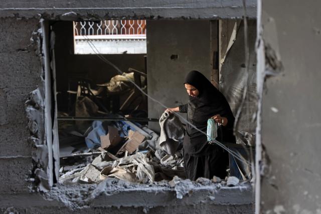 A Palestinian woman looks for her belongings inside a damaged building, a day after of an Israeli strike at the Shati refugee camp (Beach) in Gaza City, on May 9, 2026. Despite an October ceasefire, Gaza remains gripped by daily violence as Israeli strikes continue, with both the military and Hamas accusing one another of violating the truce. (Photo by Omar AL-QATTAA / AFP)