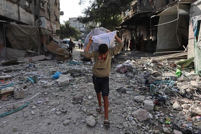 A Palestinian boy carries sacks amid the rubble of destroyed buildings, a day after of an Israeli strike at the Shati refugee camp (Beach) in Gaza City, on May 9, 2026. Despite an October ceasefire, Gaza remains gripped by daily violence as Israeli strikes continue, with both the military and Hamas accusing one another of violating the truce. (Photo by Omar AL-QATTAA / AFP)