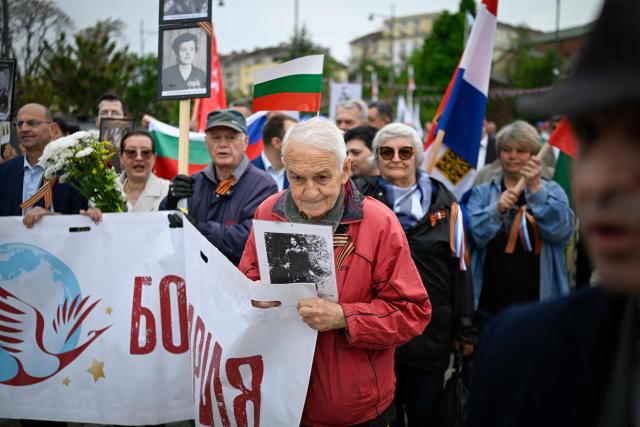 People hold portraits and wave Russian and Bulgarian flags during an "Immortal Regiment" march celebrating the Victory Day, marking the Allied victory against Nazi Germany and the end of World War II in Europe (VE Day), in Sofia, on May 9, 2026. Pro-Russian circles in Bulgaria remain divided over the prospects for improved relations with Russia following Rumen Radev’s assumption of the office of prime minister. (Photo by Nikolay DOYCHINOV / AFP)