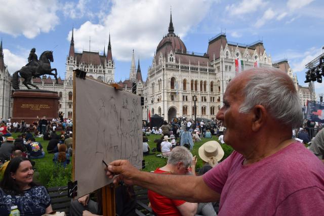 A man draws a picture as people gather in front of Hungary's parliament building in Budapest on May 9, 2026. Pro-European conservative Peter Magyar will be officially sworn in as Prime Minister by the Hungarian parliament on May 9, 2026, just under a month after his landslide victory in the parliamentary elections against nationalist Viktor Orban. (Photo by Ferenc ISZA / AFP)