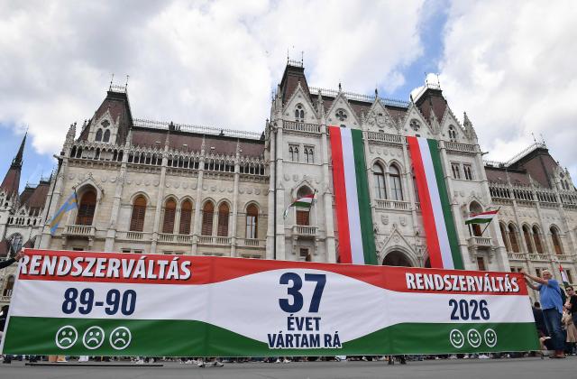 People hold a banner reading (from L to R: "Regime Change 89-90 - 37 years I was waiting for it - Regime Change 2026") outside Hungary's parliament building in Budapest on May 9, 2026. Pro-European conservative Peter Magyar will be officially sworn in as Prime Minister by the Hungarian parliament on May 9, 2026, just under a month after his landslide victory in the parliamentary elections against nationalist Viktor Orban. (Photo by Ferenc ISZA / AFP)