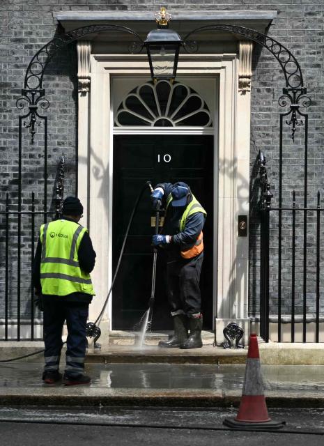 Workers clean the street outside the door to 10 Downing Street, the official residence of Britain's Prime Minister, Labour leader Keir Starmer, in central London on May 9, 2026. British Prime Minister Keir Starmer promised on Saturday he would "listen to voters" after his Labour party received a historic drubbing in local and regional elections. (Photo by JUSTIN TALLIS / AFP)