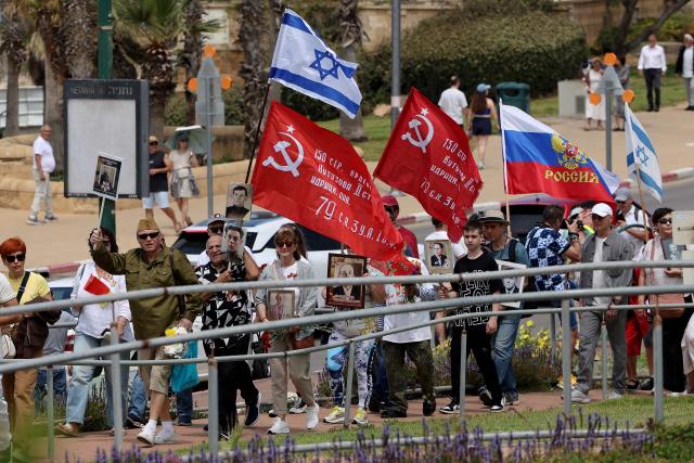 Red Army veterans participate alongside relatives and supporters wave flags  during a ceremony to commemorate the 81th anniversary of the Victory over Germany in World War II, at the Victory Monument commemorating the Red Army's victory over Nazi Germany, in the Israeli coastal city of Netanya on May 9, 2026. (Photo by JACK GUEZ / AFP)