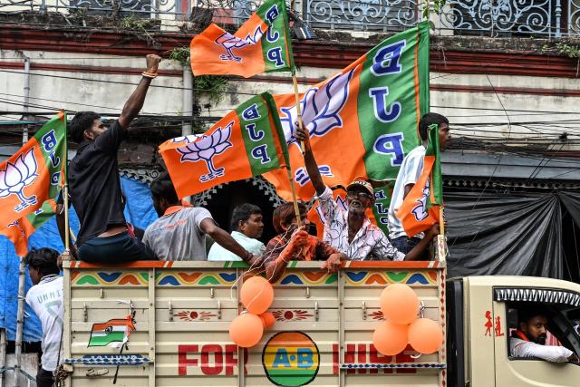 Supporters of the Bharatiya Janata Party (BJP) celebrate with the party flags as they return after attending the swearing-in ceremony of West Bengal's newly-elected Chief Minister Suvendu Adhikari in Kolkata on May 9, 2026. (Photo by Dibyangshu SARKAR / AFP)