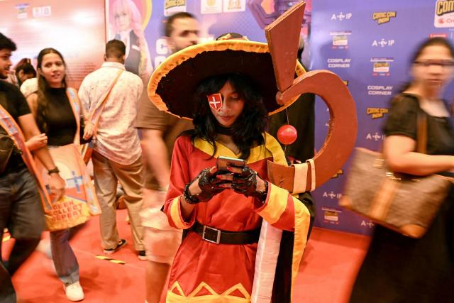 A cosplayer checks her phone during the Mumbai Comic Con 2026 festival in Mumbai on May 9, 2026. (Photo by Indranil MUKHERJEE / AFP)