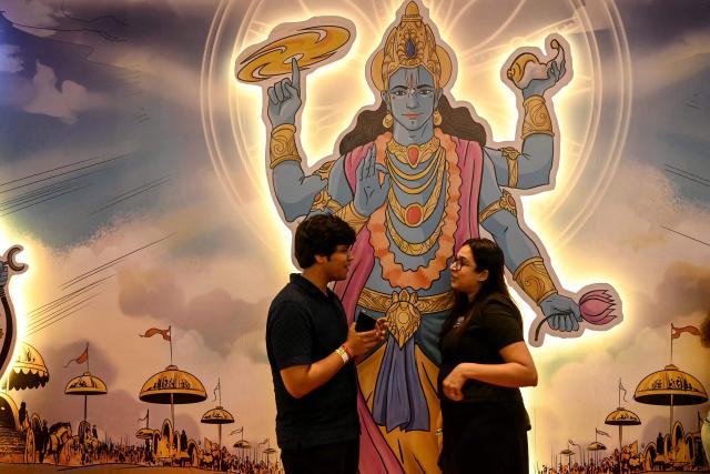 Fans stand next to a poster of Hindu deity Ram, displayed outside a stall during the Mumbai Comic Con 2026 festival in Mumbai on May 9, 2026. (Photo by Indranil MUKHERJEE / AFP)