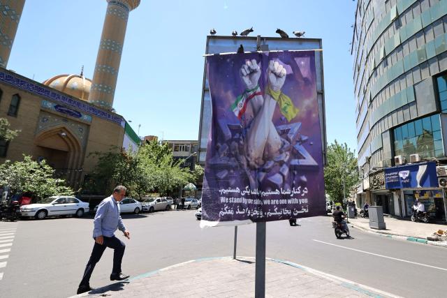 A banner depicting an Iranian fist (L) and a Lebanese Shia Muslim party Hezbollah fist punching through an Israeli  Star of David, hangs on a street in the capital Tehran on May 9, 2026. Iran questioned the seriousness of American diplomacy on May 9, in the wake of renewed naval clashes in the Gulf, while keeping Washington waiting for a response to its latest negotiating position. On February 28, 2026, Israel and the United States launched strikes on Iran, killing its supreme leader and triggering a war that spread across the Middle East. (Photo by ATTA KENARE / AFP) / 