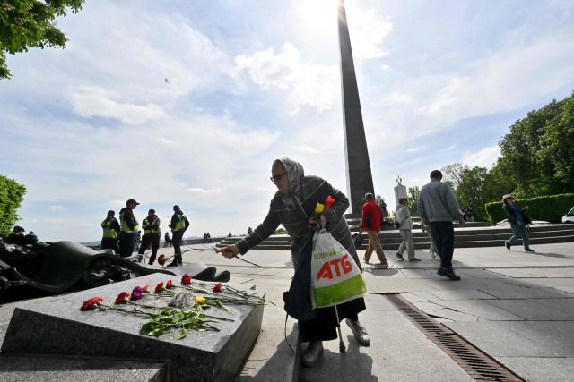 A woman lays flowers on the Tomb of the Unknown Soldier to mark the Victory Day over Nazism in World War II, at the Eternal Glory park in Kyiv on May 9, 2026, amid the Russian invasion of Ukraine. (Photo by Sergei SUPINSKY / AFP)