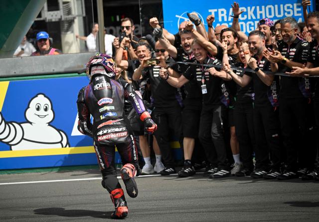 TOPSHOT - Aprilia Racing's Spanish rider Jorge Martin (L) runs to celebrates with his team after winning the Moto GP Grand Prix of France Sprint race at Le Mans, northwestern France, on May 9, 2026. (Photo by Loic VENANCE / AFP)