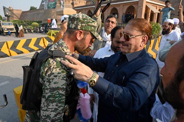 Pakistan Muslim League Nawaz (PMLN) party supporters greet paramilitary personnel with garlands during a rally to mark one year since the India-Pakistan conflict, outside the Frontier Corps headquarters in Peshawar on May 9, 2026. (Photo by Abdul MAJEED / AFP)