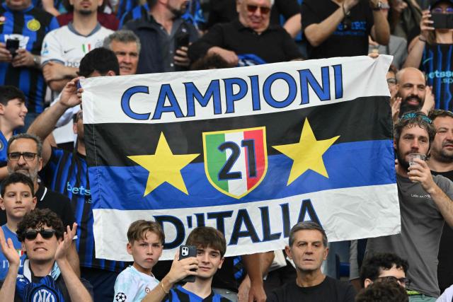 Inter Milan's supporters hold a flag reading "Champions of Italy" and bearing the colours of InterMilan as they cheer for their team ahead of the Italian Serie A football match between Lazio and InterMilan at the Olympic stadium in Rome on May 9, 2026. (Photo by Alberto PIZZOLI / AFP)