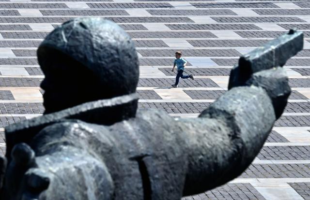 A boy runs past the monument "Crossing of the Dnieper" at the National Museum of the History of Ukraine in the World War II, a day after the Victory Day over Nazism in World War II, in Kyiv on May 9, 2026, amid the Russian invasion of Ukraine.  (Photo by Sergei SUPINSKY / AFP)