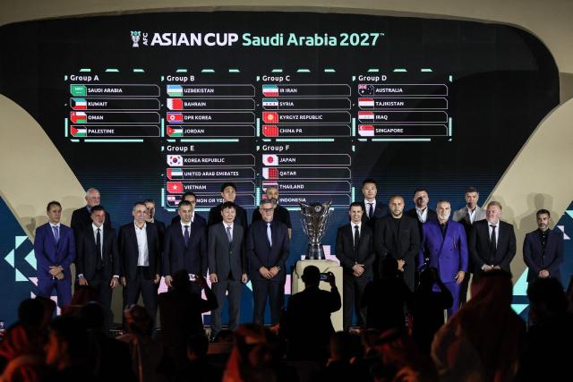 Coaches of Asian national football teams pose in front of a screen showing the results of the final draw for the 2027 AFC Asian Cup during a ceremony in Diriyah, on the outskirts of Riyadh, on May 9, 2026. The 19th edition of the Asian Cup is scheduled to take place from January 7 to February 5 next year in Saudi Arabia. (Photo by Fayez NURELDINE / AFP)