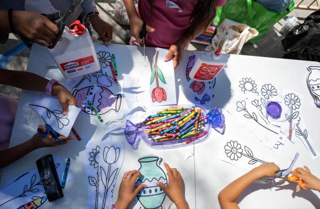 Migrant children paint and cut paper flowers for their mothers as part of mother's Day celebrations for migrant mothers at Comunidad de Luz shelter in Tijuana, Baja California state, Mexico on May 9, 2026. (Photo by Guillermo Arias / AFP)