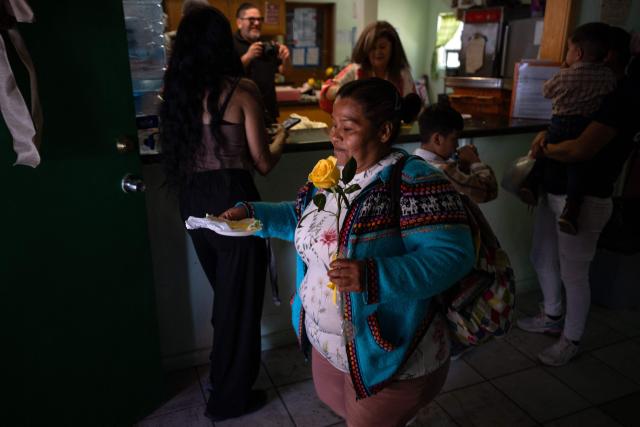 A migrant mother receives flowes and a piece of cake as part of mother's Day celebrations at Comunidad de Luz shelter in Tijuana, Baja California state, Mexico on May 9, 2026. (Photo by Guillermo Arias / AFP)