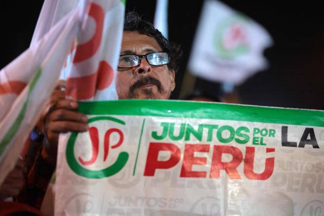 A supporter of Peru's presidential candidate Roberto Sanchez, for the Juntos por el Peru party, holds a party banner during a rally in Huaycan community in Lima, Peru on May 9, 2026. (Photo by Connie FRANCE / AFP)