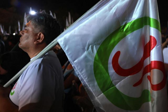 A supporter of Peru's presidential candidate Roberto Sanchez, for the Juntos por el Peru party, holds a party flag during a rally in Huaycan community in Lima, Peru on May 9, 2026. (Photo by Connie FRANCE / AFP)