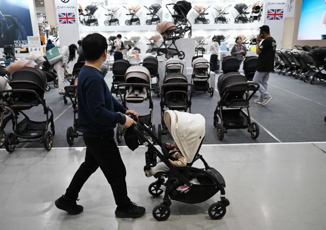 This picture taken on April 30, 2026 shows a man pushing a stroller as he visits a baby fair in Seoul. South Korea has one of the world's lowest birth rates, and the government has spent billions of dollars trying to encourage citizens to have more babies and cushion the worst impacts of a shrinking population. The Asian nation is still nowhere near reversing the trend, but a modest baby bump is offering a glimmer of hope after years of bleak statistics. (Photo by Jung Yeon-je / AFP) / TO GO WITH AFP STORY  SKorea-demographics / FOCUS BY Matthew Walsh and Jihye Shin