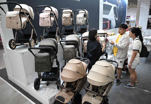 This picture taken on April 30, 2026 shows visitors looking at strollers at a booth during a baby fair in Seoul. South Korea has one of the world's lowest birth rates, and the government has spent billions of dollars trying to encourage citizens to have more babies and cushion the worst impacts of a shrinking population. The Asian nation is still nowhere near reversing the trend, but a modest baby bump is offering a glimmer of hope after years of bleak statistics. (Photo by Jung Yeon-je / AFP) / TO GO WITH AFP STORY  SKorea-demographics / FOCUS BY Matthew Walsh and Jihye Shin