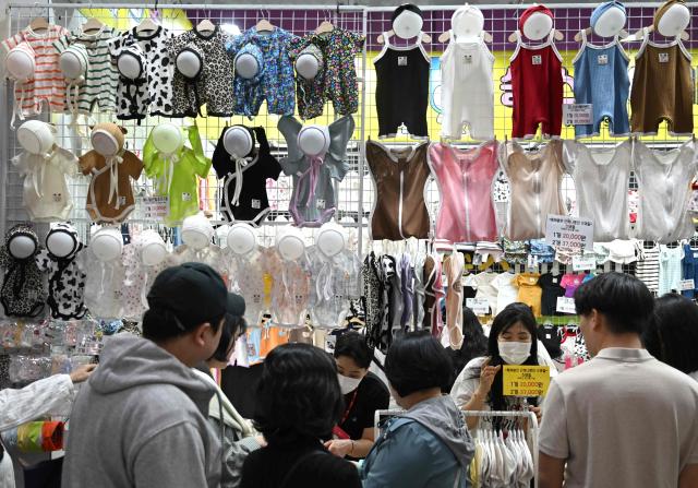 This picture taken on April 30, 2026 shows baby clothes displayed at a booth during a baby fair in Seoul. South Korea has one of the world's lowest birth rates, and the government has spent billions of dollars trying to encourage citizens to have more babies and cushion the worst impacts of a shrinking population. The Asian nation is still nowhere near reversing the trend, but a modest baby bump is offering a glimmer of hope after years of bleak statistics. (Photo by Jung Yeon-je / AFP) / TO GO WITH AFP STORY  SKorea-demographics / FOCUS BY Matthew Walsh and Jihye Shin