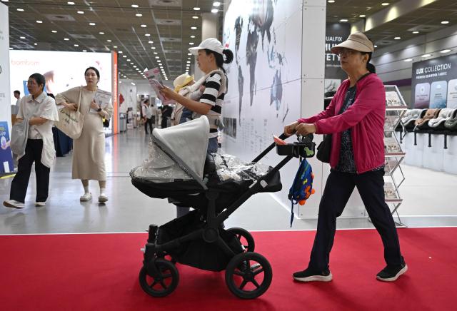 This picture taken on April 30, 2026 shows a woman pushing a stroller as she visits a baby fair in Seoul. South Korea has one of the world's lowest birth rates, and the government has spent billions of dollars trying to encourage citizens to have more babies and cushion the worst impacts of a shrinking population. The Asian nation is still nowhere near reversing the trend, but a modest baby bump is offering a glimmer of hope after years of bleak statistics. (Photo by Jung Yeon-je / AFP) / TO GO WITH AFP STORY  SKorea-demographics / FOCUS BY Matthew Walsh and Jihye Shin