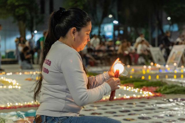 A woman lights a candle during a vigil by Mexican search collectives for missing persons at the Monument to the Mother in Mexico City on May 9, 2026, a day before the national march by the Mothers of the Disappeared on Mother's Day. (Photo by GERARDO MAGALLON / AFP)