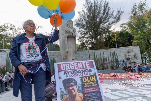 A woman stands with balloons and a sign during a vigil by Mexican search collectives for missing persons at the Monument to the Mother in Mexico City on May 9, 2026, a day before the national march by the Mothers of the Disappeared on Mother's Day. (Photo by GERARDO MAGALLON / AFP)