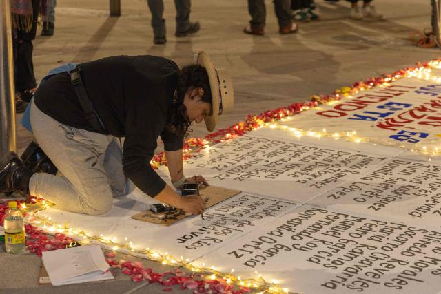 A demonstrator writes names during a vigil by Mexican search collectives for missing persons at the Monument to the Mother in Mexico City on May 9, 2026, a day before the national march by the Mothers of the Disappeared on Mother's Day. (Photo by GERARDO MAGALLON / AFP)
