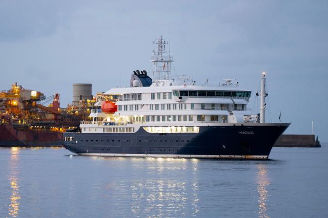 TOPSHOT - The Dutch flagged hantavirus-stricken cruise ship MV Hondius arrives to the industrial port of Granadilla de Abona on the island of Tenerife in Spain's Canary Islands to commence evacuation of passengers and most crew members on May 10, 2026. Repatriation flights for the nearly 150 passengers onboard the ship hit by a deadly hantavirus outbreak are planned to the United States, Britain, France,  and other countries, Spain's interior minister announced on Saturday.  Passengers will be transferred to shore on a smaller vessel then by bus to the airport and then flown home after weeks at sea. (Photo by JORGE GUERRERO / AFP)