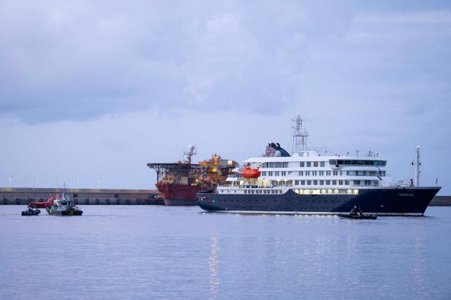 The Dutch flagged hantavirus-stricken cruise ship MV Hondius arrives to the industrial port of Granadilla de Abona on the island of Tenerife in Spain's Canary Islands to commence evacuation of passengers and most crew members on May 10, 2026. Repatriation flights for the nearly 150 passengers onboard the ship hit by a deadly hantavirus outbreak are planned to the United States, Britain, France,  and other countries, Spain's interior minister announced on Saturday.  Passengers will be transferred to shore on a smaller vessel then by bus to the airport and then flown home after weeks at sea. (Photo by JORGE GUERRERO / AFP)