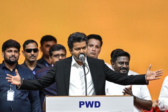 Newly elected chief minister of India's Tamil Nadu state, C. Joseph Vijay (C) takes an oath during his swearing-in ceremony in Chennai on May 10, 2026. Indian film superstar C. Joseph Vijay was on May 10 sworn in as chief minister of Tamil Nadu state, after his party emerged as the single largest following elections in the industrial hub. (Photo by R.Satish BABU / AFP)