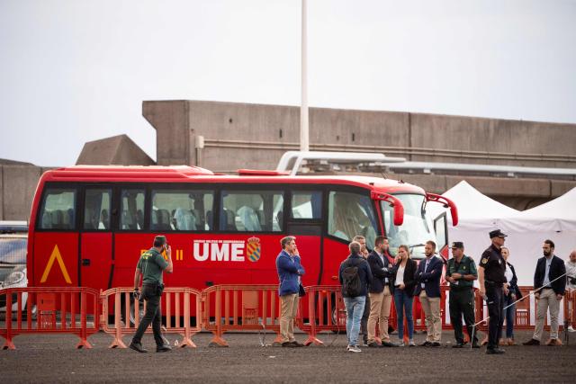 Authorities stand by a military bus which will be used to transfer evacuees from the Dutch flagged hantavirus-stricken cruise ship MV Hondius at the industrial port of Granadilla de Abona on the island of Tenerife in Spain's Canary Islands on May 10, 2026. Repatriation flights for the nearly 150 passengers onboard the ship hit by a deadly hantavirus outbreak are planned to the United States, Britain, France,  and other countries, Spain's interior minister announced on Saturday. Most of the nearly 150 people on board will be transferred to shore on smaller vessels then by bus to the airport and then flown home after weeks at sea. (Photo by JORGE GUERRERO / AFP)