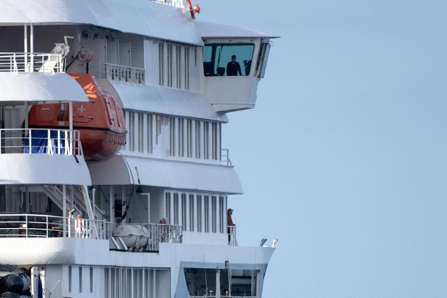 People are seen aboard the Dutch flagged hantavirus-stricken cruise ship MV Hondius after it arrived at the industrial port of Granadilla de Abona on the island of Tenerife in Spain's Canary Islands on May 10, 2026. Repatriation flights for the nearly 150 passengers onboard the ship hit by a deadly hantavirus outbreak are planned to the United States, Britain, France,  and other countries, Spain's interior minister announced on Saturday. Most of the nearly 150 people on board will be transferred to shore on smaller vessels then by bus to the airport and then flown home after weeks at sea. (Photo by JORGE GUERRERO / AFP)