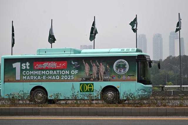 A government passenger bus carrying a poster of Pakistan's Army Chief and Field Marshal Syed Asim Munir (center, L) moves along a road in Islamabad on May 10, 2026 commemorating one year of India-Pakistan clashes after an attack in Indian-administered Kashmir.  (Photo by Aamir QURESHI / AFP)